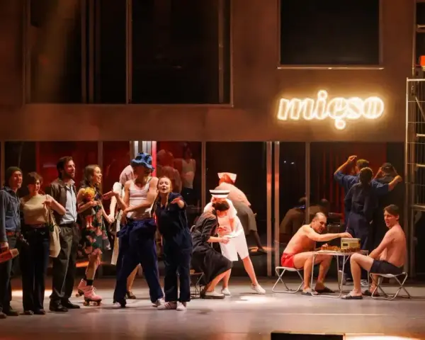 Scena z musicalu "1989". Aktorzy w strojach z epoki, neon "mięso" w tle.