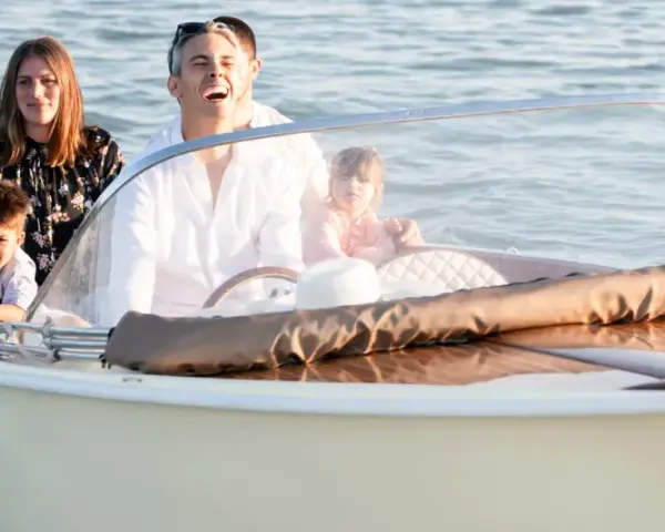 Famiglia felice su un barchino a Venezia, con bambini che guardano l'acqua.