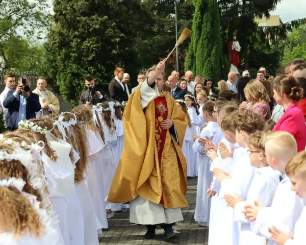Uroczystość I Komunii Świętej. Dzieci w bieli, ksiądz błogosławi. Zastanawiasz się, ile kosztuje talerzyk na komunie?