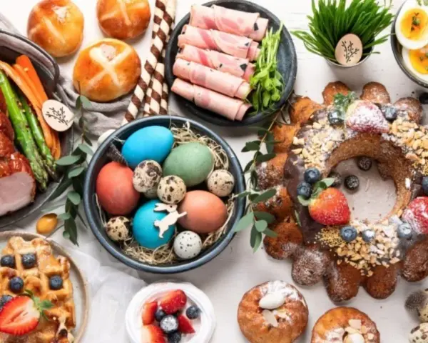A festive Easter feast in Europe, featuring a glazed ham, colorful eggs, sweet breads, and a decorated cake.