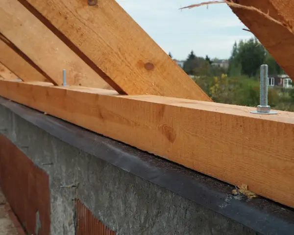 Murłata, czyli belka drewniana, mocowana do wieńca, stanowi podstawę konstrukcji dachu. Widać ją na tle nieba i drzew.
