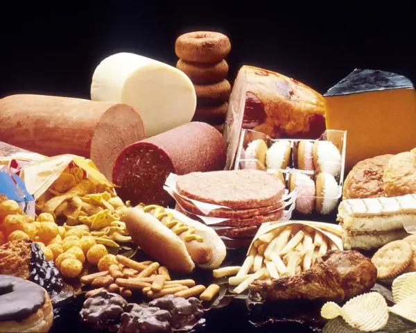 Stół ugina się pod ciężarem przetworzonej żywności: wędliny, sery, frytki, słodycze, ciastka, pączki, hamburgery i chipsy – to wszystko zawiera tłuszcze trans.