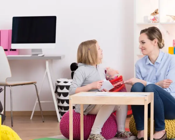 Terapeutka wspiera dziewczynkę w terapii afazji u dzieci, pracując nad komunikacją i rozwojem mowy.