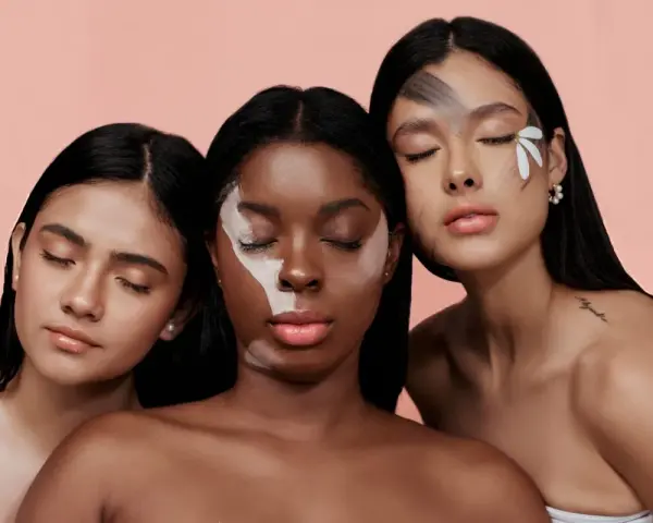 Tre donne con diverse tonalità di pelle, una con un trucco artistico sul viso, evocano la bellezza naturale e l'efficacia del palmitoyl tripeptide-1.