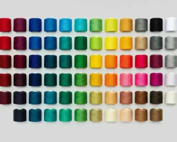 Una gran variedad de tipos de hilos de coser en carretes, organizados por color en filas y columnas.