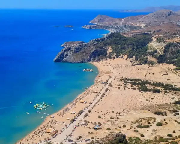 Malownicze plaże Rodos z turkusową wodą, piaszczystym wybrzeżem, leżakami i wodnym parkiem rozrywki.