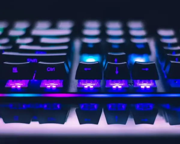 Zbliżenie na klawiaturę gamingową z kolorowym podświetleniem RGB. Widoczne klawisze Shift, Ctrl i strzałki. Różne rodzaje klawiatur oferują unikalne wrażenia.