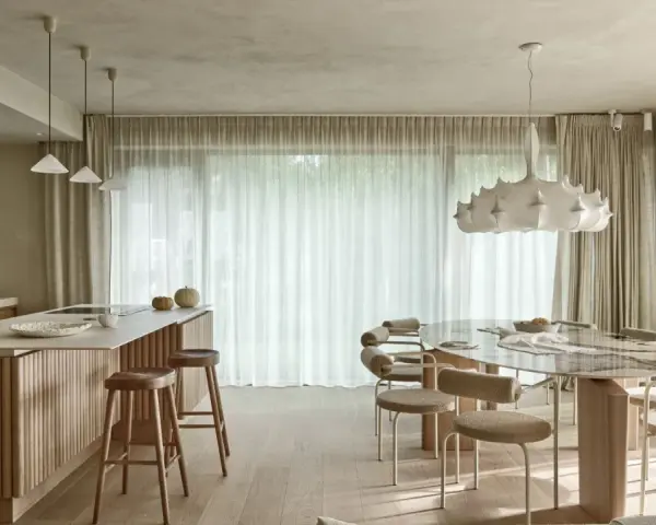 Nowoczesna kuchnia z wyspą i jadalnią. Wnętrze rozświetla designerska lampa wisząca, a całość dopełnia podwieszany sufit.