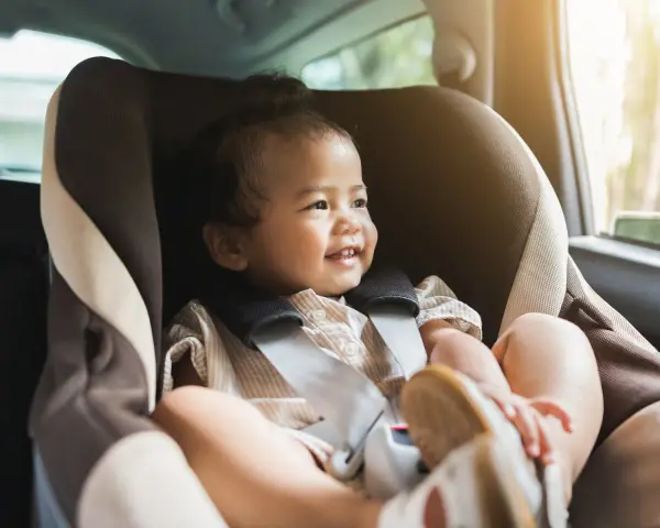 Glückliches Kleinkind im Kindersitz, bereit für eine Fahrt. Ein reboarder test zeigt, wie sicher es ist.