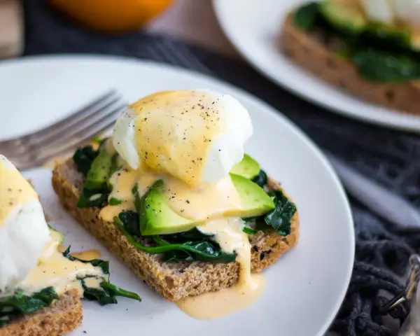 Pyszne jajka po florencku na tostach z awokado i szpinakiem, polane sosem holenderskim. Idealne na brunch!