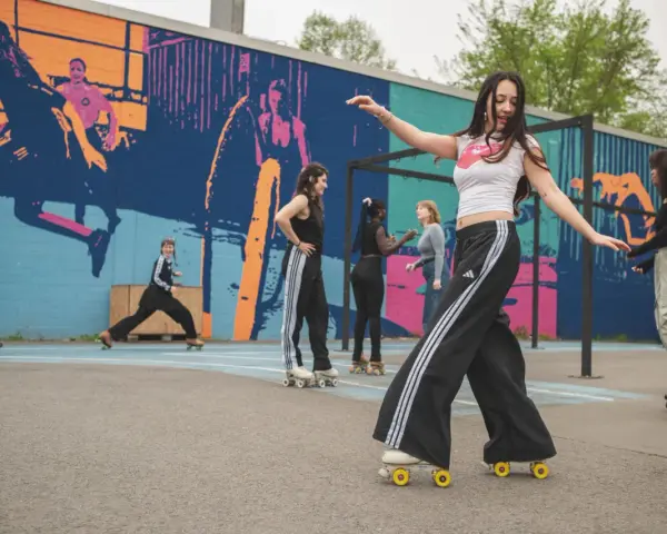 Eine Gruppe junger Leute genießt das Roller-Skating in Berlin vor einer bunten Wandmalerei.