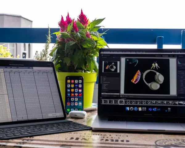 iPad Pro mit Tastatur, iPhone, AirPods und MacBook Pro mit Kopfhörern und Schlüsseln.