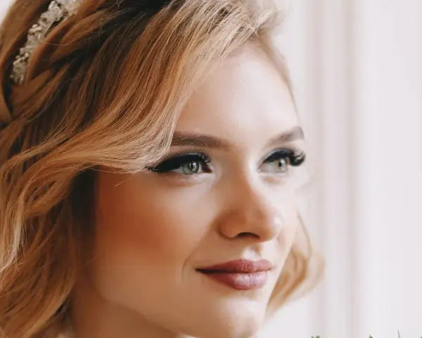Eleganckie upięcia krótkich włosów na wesele z warkoczem i ozdobą. Delikatne fale i subtelny makijaż podkreślają urodę panny młodej.