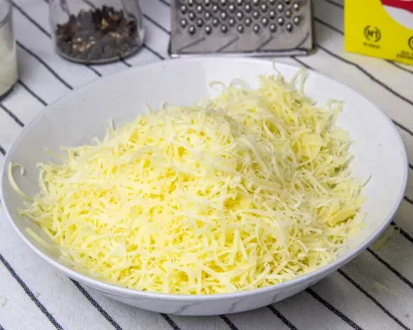 Queso rallado en un bol blanco, listo para hacer fondue.