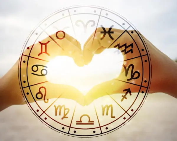 Dłonie tworzą serce, a w tle koło zodiaku z symbolem koziorożca. Miłość i astrologia, czyli koziorożec i koziorożec w sercu.