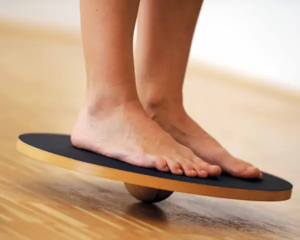 Piedi su una tavola di equilibrio, utili per esercizi di riabilitazione per distorsione caviglia.