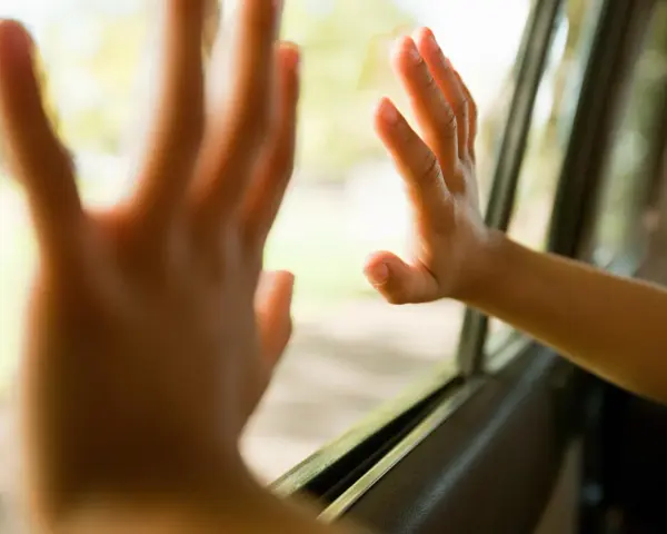 Dziecko z podwrażliwością dotykową delikatnie dotyka szyby samochodu, czując świat za nią.