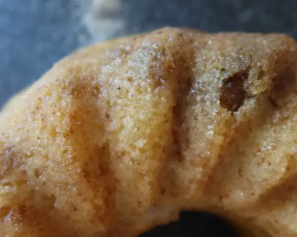 Närbild på en gyllene sockerkaka med kardemumma, med synliga små prickar av kryddan i den porösa kakan.