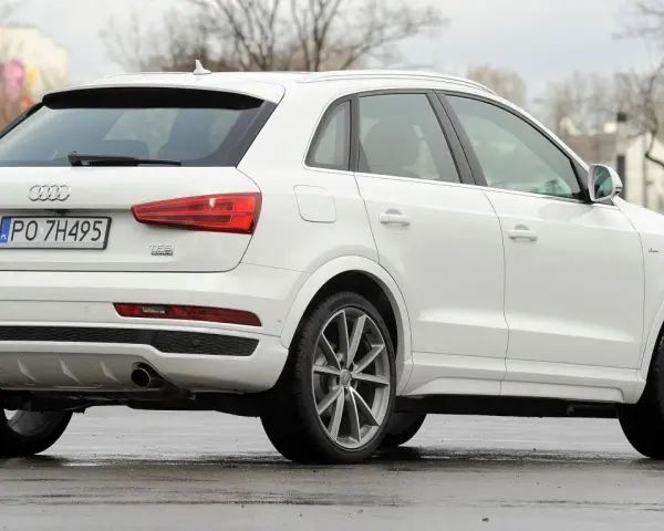 Biały SUV Audi Q3, idealny suv do 70 tys. zł, z polskimi tablicami rejestracyjnymi PO 7H495, widoczny z tyłu i z boku.