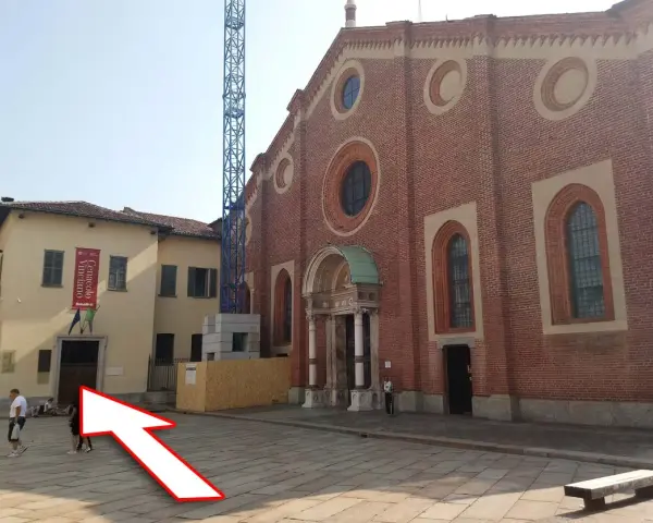 Plac przed kościołem z banerem "Cenacolo Vinciano". Bilety na Ostatnią Wieczerzę można kupić w pobliżu.