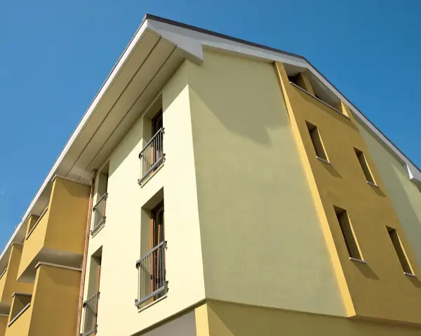 Edificio moderno con facciata bicolore, protetta da vernice isolante termica Mapei, sotto un cielo azzurro.