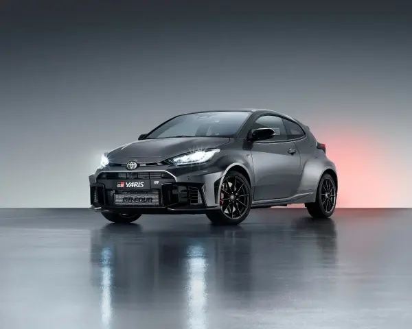 Szary Toyota GR Yaris GR-FOUR z agresywnym przednim zderzakiem i czarnymi felgami, gotowy do podboju dróg.