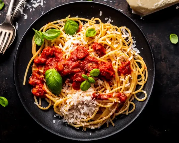 Talerz spaghetti z sosem pomidorowym, parmezanem i bazylią.