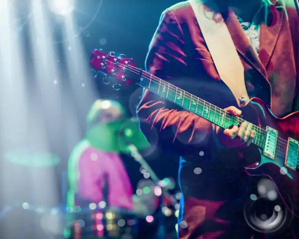 Koncertowe emocje! Gitarzysta gra na scenie, a w tle widać perkusistę. To jakby występ znanych zespołów muzycznych zagranicznych.