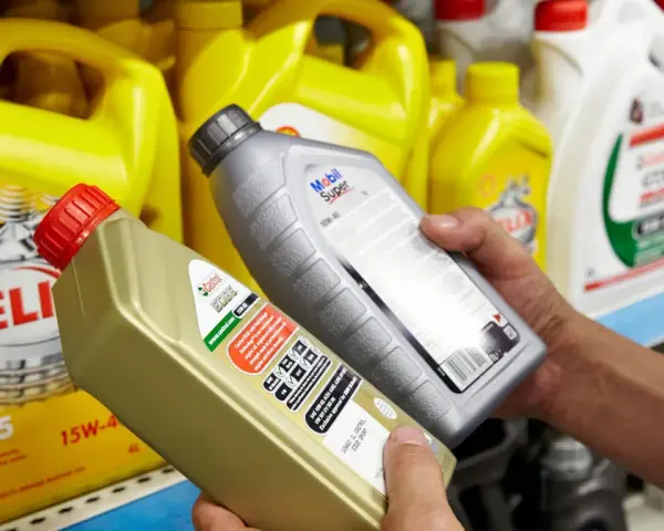 Wybierasz jaki olej do silnika? Na półce stoją różne marki: Shell Helix, Castrol Edge i Mobil Super.