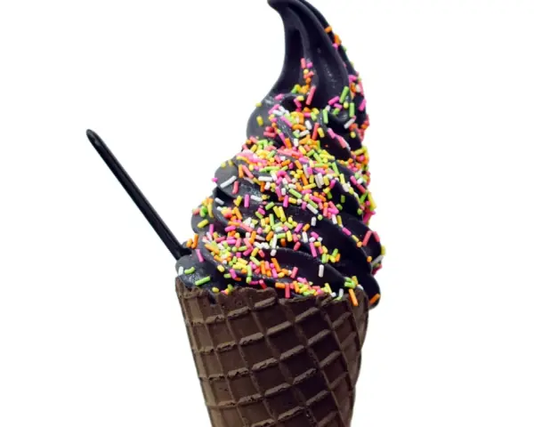 Schwarzes Eis in einer Waffel, bestreut mit bunten Streuseln. Ein schwarzer Löffel steckt darin.