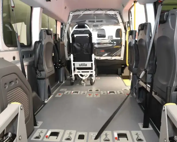 Innenraum eines Rollstuhlfahrzeugs, das als Taxi-Ersatz dient. Sitze und Rollstuhlhalterungen sind sichtbar.