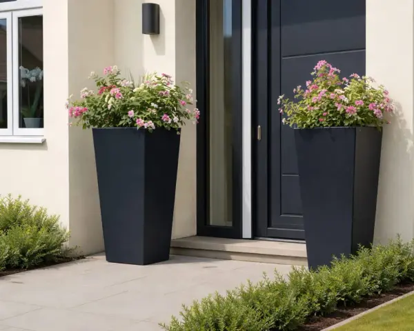 Zwei hohe, dunkle Pflanzkübel mit rosa und weißen Blüten schmücken den Eingangsbereich. Ein schöner Weg, den hauseingang zu bepflanzen.