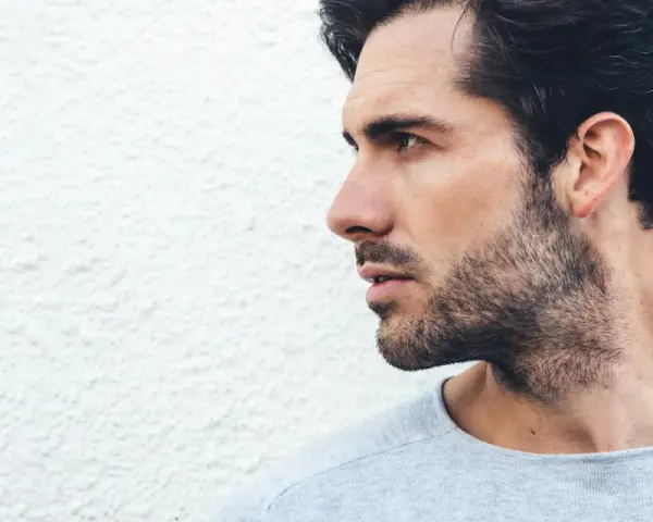 Perfil de hombre con barba, pensando hasta donde afeitarse el cuello.