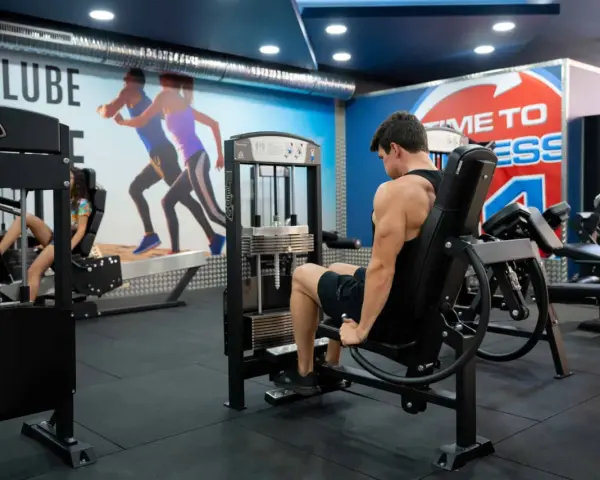 Man tränar ben på en **floor press**-maskin i ett modernt gym.