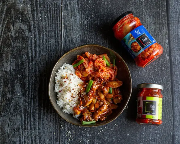 Miseczka z ryżem i kurczakiem po koreańsku, z dodatkiem kimchi i sosu chili.