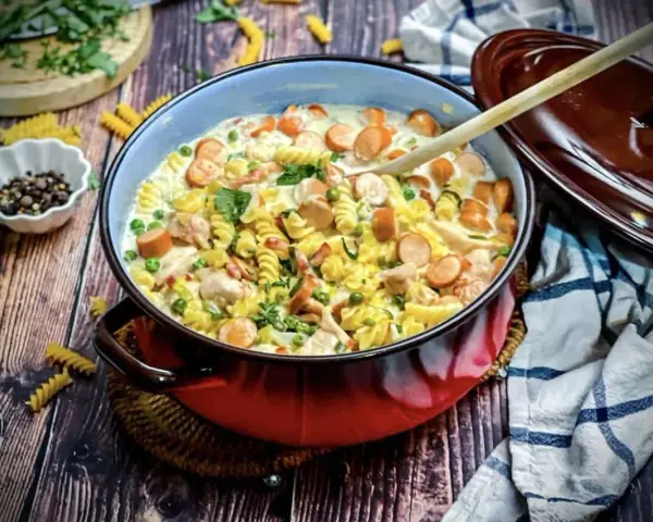 Herzhafte Nudelpfanne mit Würstchen, Erbsen und Hähnchen – ein Gericht, das perfekt für "das perfekte Dinner Rezepte" ist.