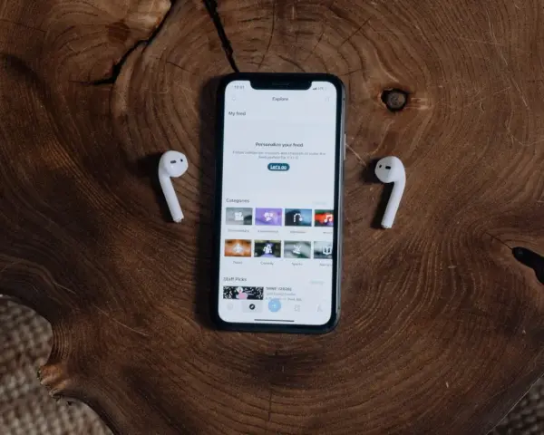 iPhone z AirPods na drewnianym tle.