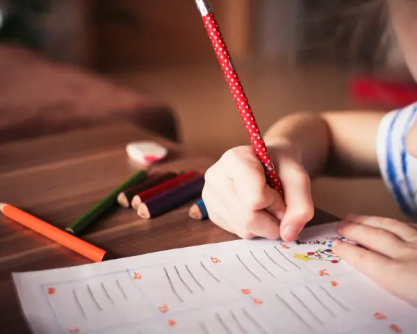 Dziecko zmagające się z dysleksją, dysgrafią, dysortografią i dyskalkulią pisze kredkami.