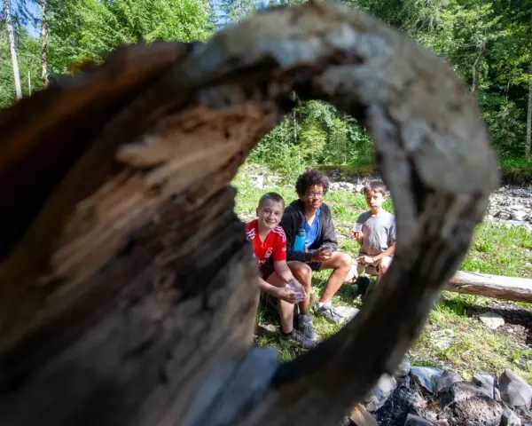 Trois enfants profitent d'une pause en forêt, rappelant l'importance du respect des locaux et de la nature.