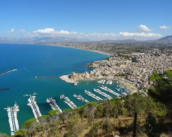Vista panoramica di Castellammare del Golfo, con il castello, il porto turistico pieno di barche e la costa siciliana.
