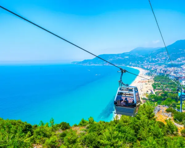 Kolejka linowa nad turkusowym morzem i plażą w Alanyi. Widok z góry na miasto i wybrzeże. Czy Alanya jest bezpieczna? Tak, wygląda na spokojną i piękną.