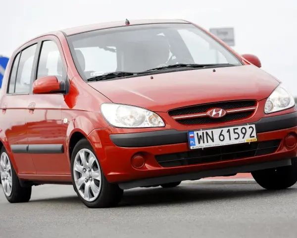 Czerwony Hyundai Getz na drodze. Kierowca za kierownicą, widoczna tablica rejestracyjna WN 61592.