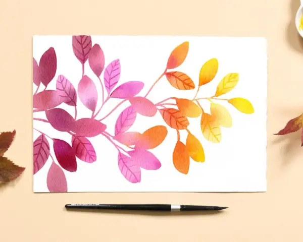 Aquarelle feuilles aux teintes roses, oranges et jaunes, évoquant l'automne. Une palette de couleurs et un pinceau sont disposés à côté.