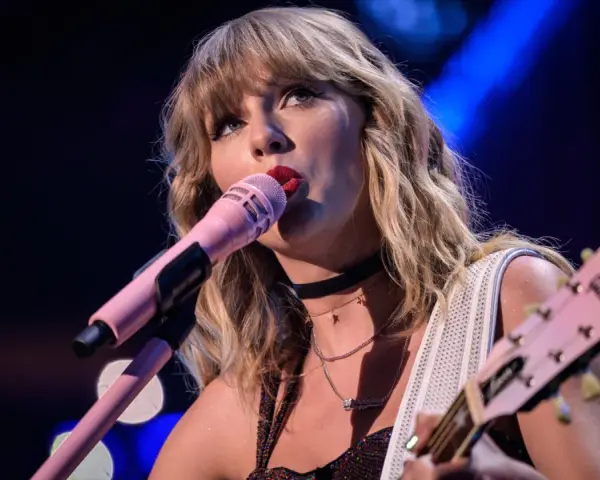 Taylor Swift śpiewa do różowego mikrofonu, grając na gitarze. To scena z jej epickiej trasy "reputation stadium tour", która na zawsze zmieniła jej wizerunek.