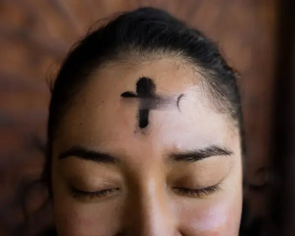 A cross of ashes marks a forehead, a solemn reminder of scripture for Ash Wednesday.