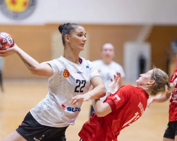 Piłkarka Suzuki Korona Handball Kielce rzuca piłkę. Rywalka w czerwonej koszulce próbuje ją zablokować.