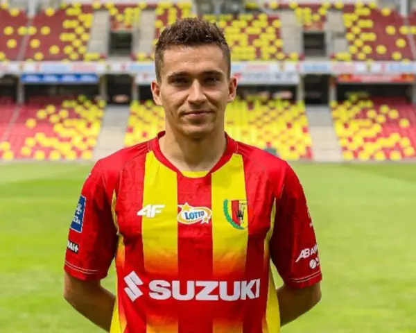 Piłkarz Korony Kielce w czerwono-żółtej koszulce na tle stadionu. Czekamy na kolejne transfery Korona Kielce!