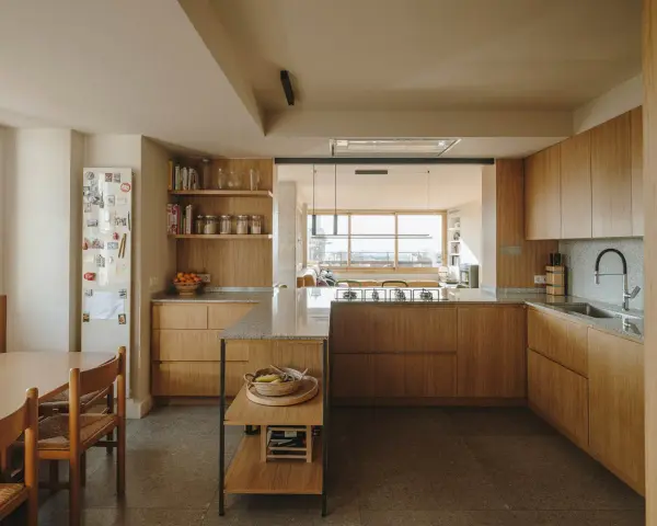 Cocinas color madera con encimeras de granito, electrodomésticos integrados y una isla central. Un comedor adyacente con mesa y sillas de madera.