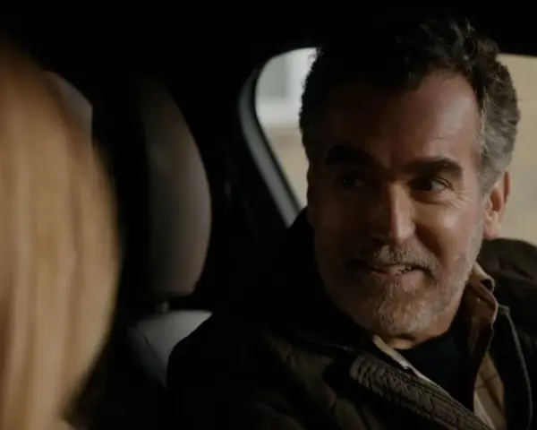 Un uomo sorride in auto, un momento di complicità nella serie turca "La Famiglia".