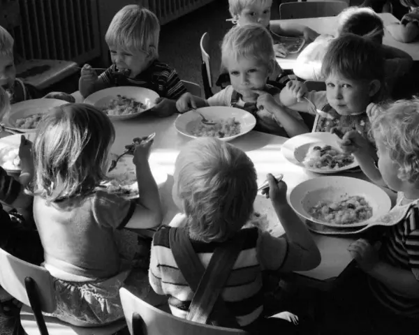 Kinder essen gemeinsam Brei. Ein Junge isst genüsslich, ein anderes Kind schaut nachdenklich. Erinnerungen an Kindheits Eis.